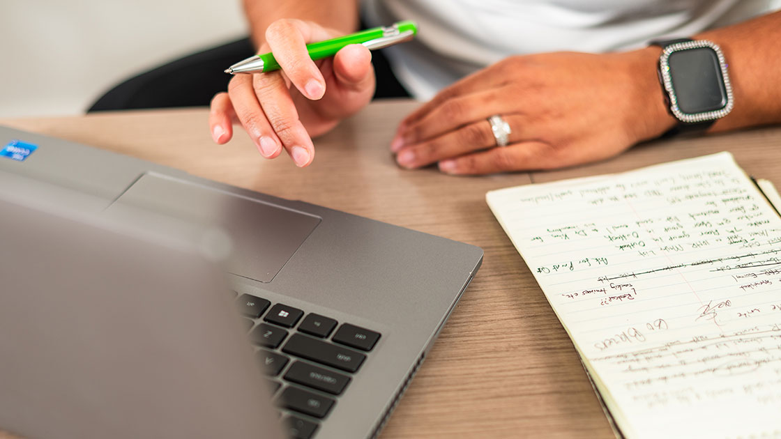 UAB employee looks at a laptop and takes notes on a pad