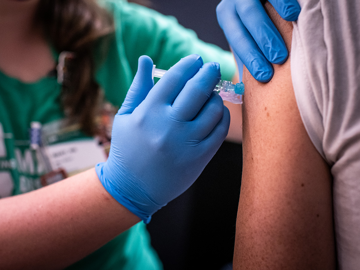 Blue gloved hands of a UAB nurse administering a flu shot at a UAB flu clinic