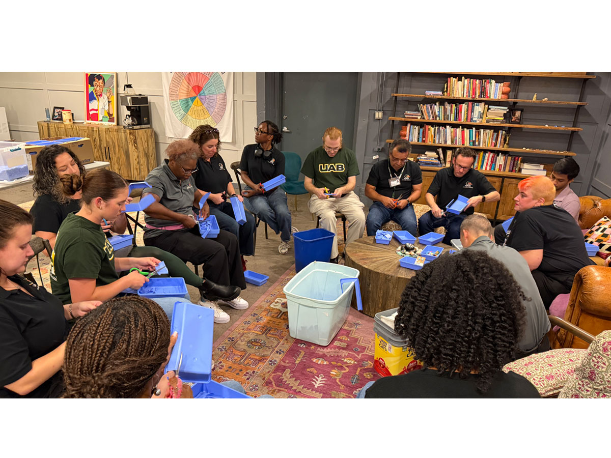 Staff from the UAB Office of Innovative Teaching and Academic Engagement gather in a circle to trim surgical trays at local nonprofit Community on the Rise
