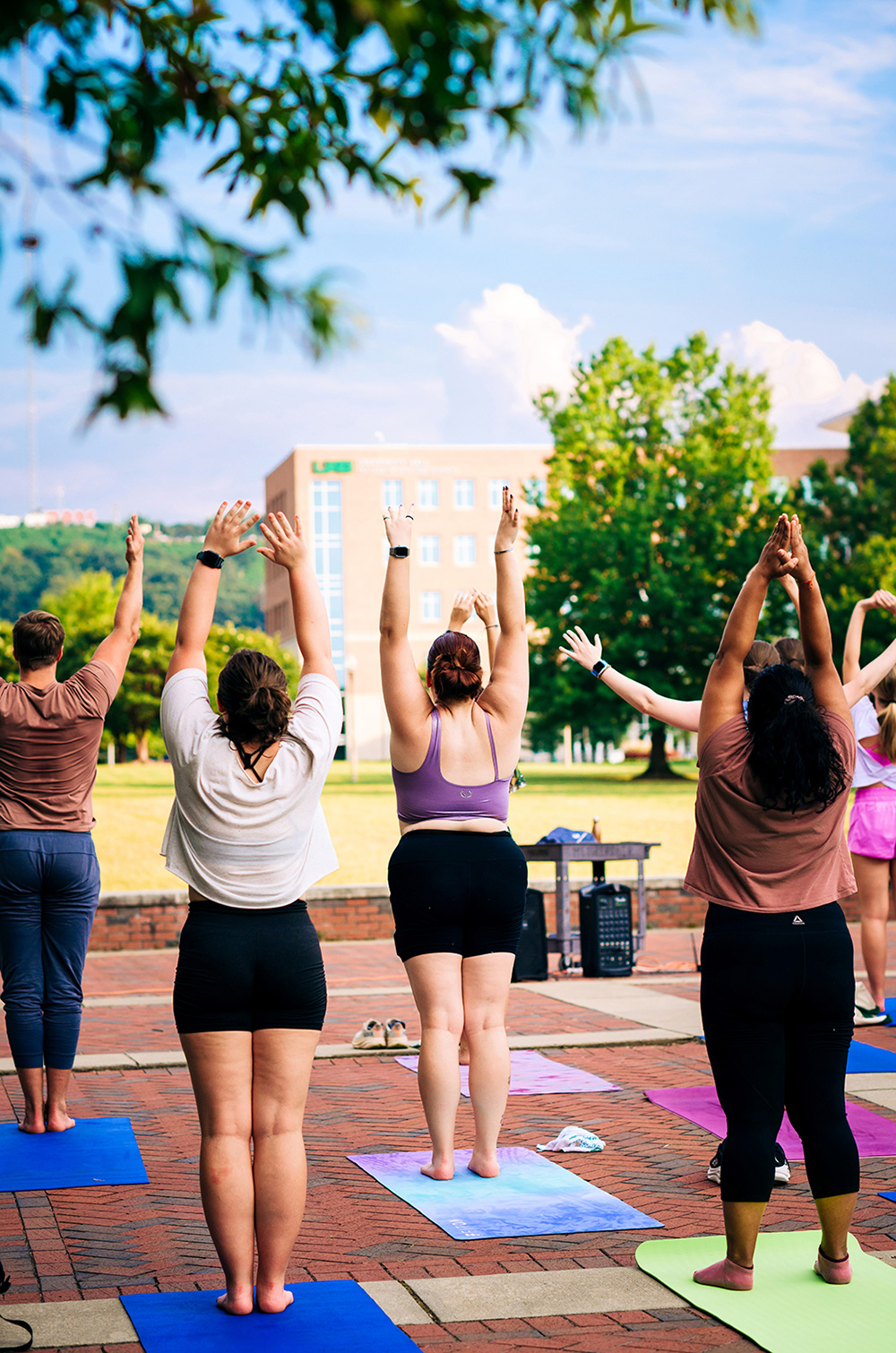 A group of students and employees doing yoga on the Campus Green