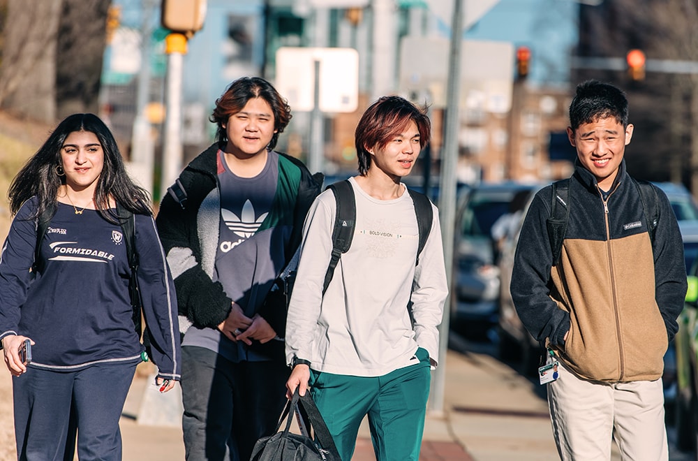 Four students walk down 10th Avenue in the winter light