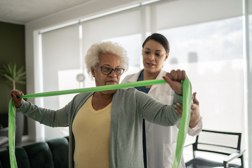 PT working with senior client using green band.