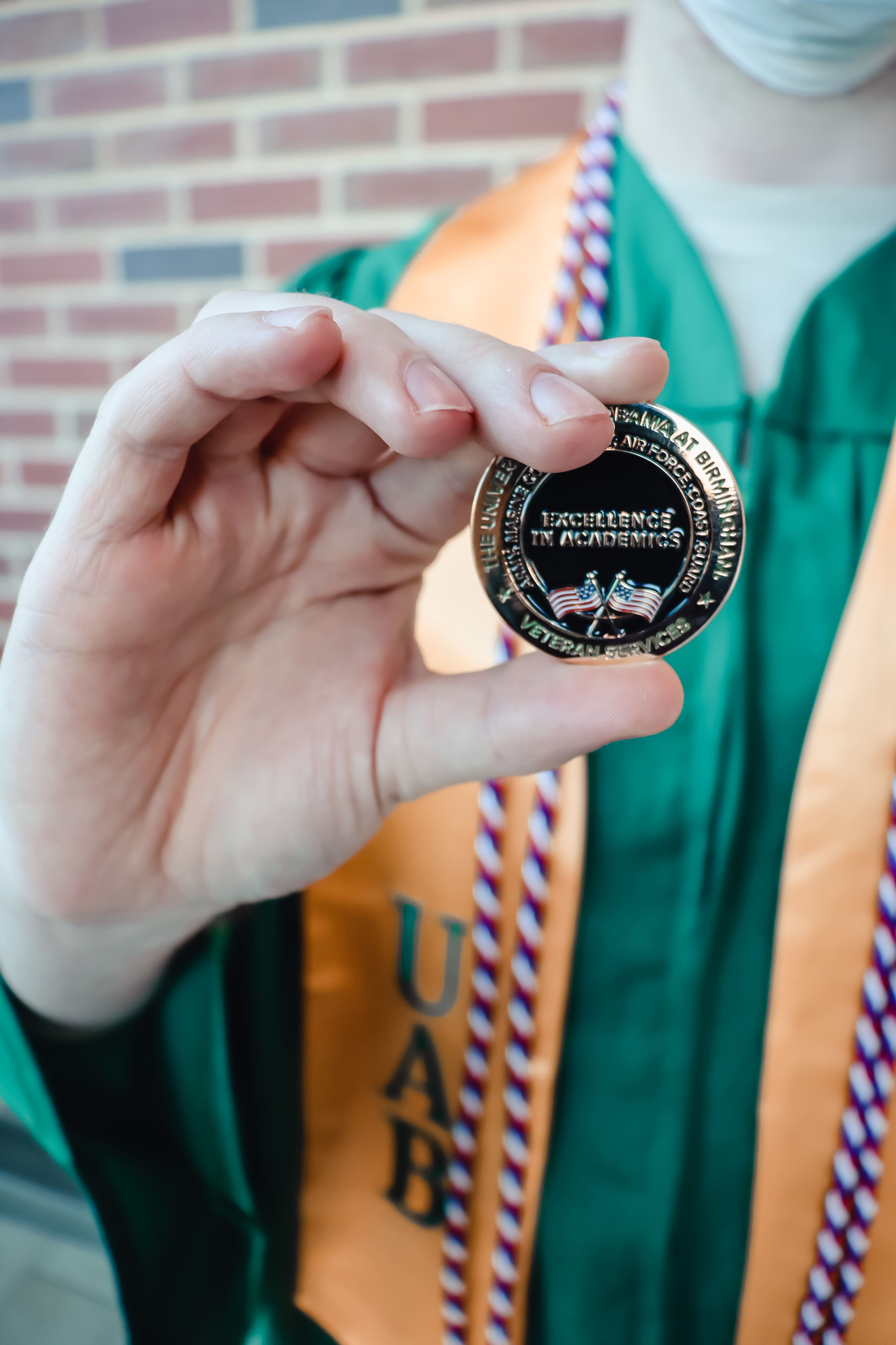 Student model holding up the Veterans Services ceremonial coin