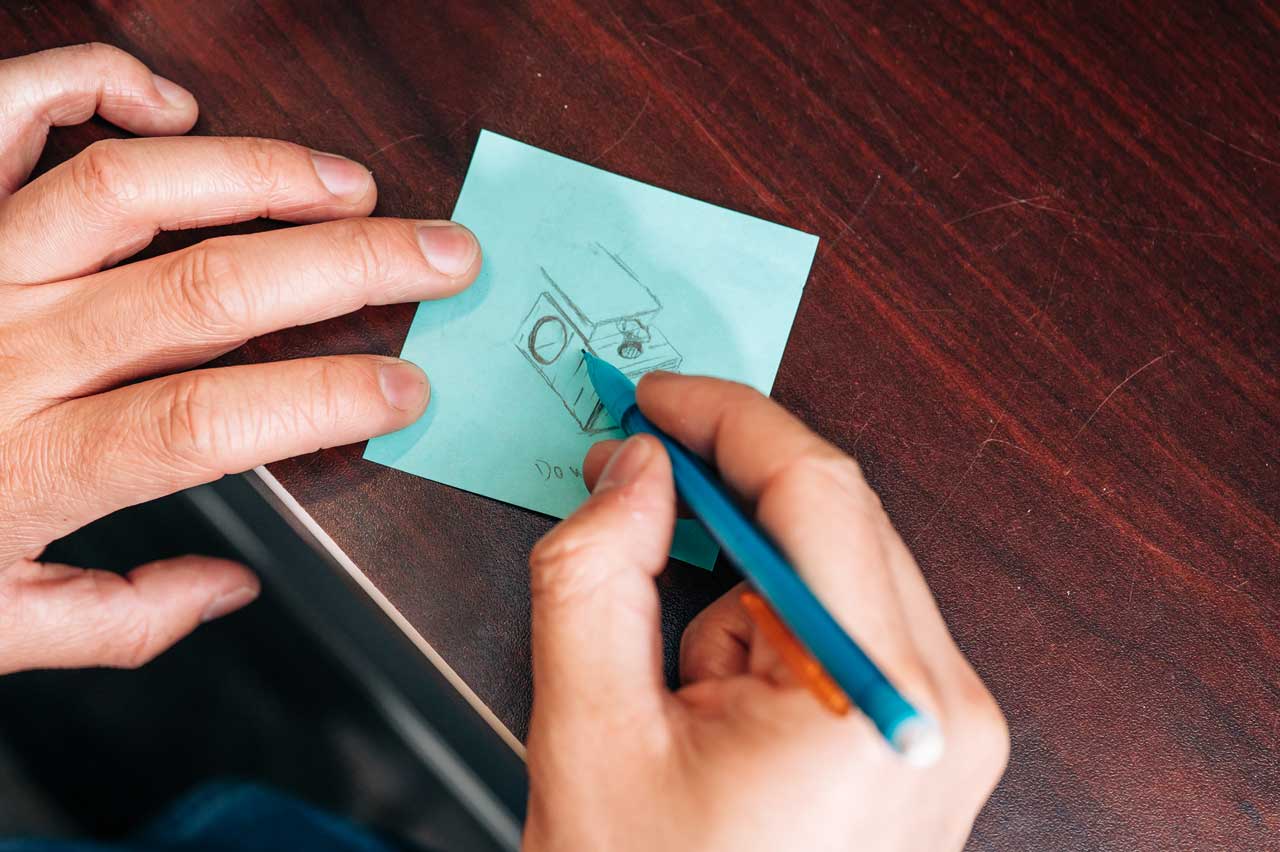 Hollingsworth sketches a component design on a sticky note.