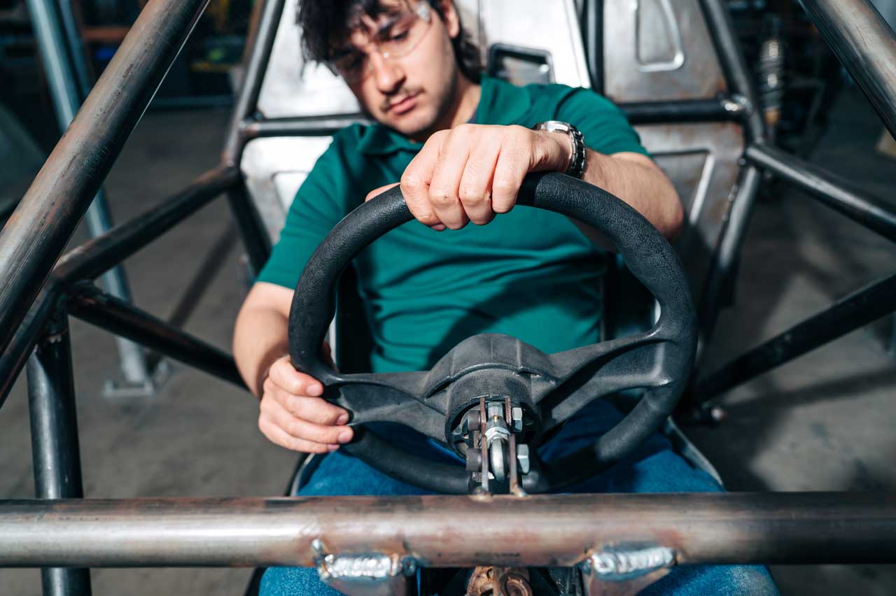 Hollingsworth sits at the steering wheel of a student-built Baja car.